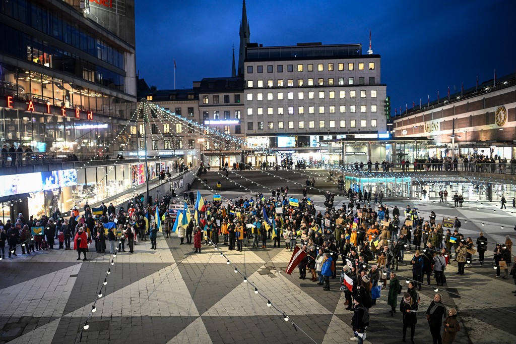 Demonstranten halten während einer Demonstration in Stockholm, Schweden, ukrainische Flaggen und Antikriegsbanner hoch. 
