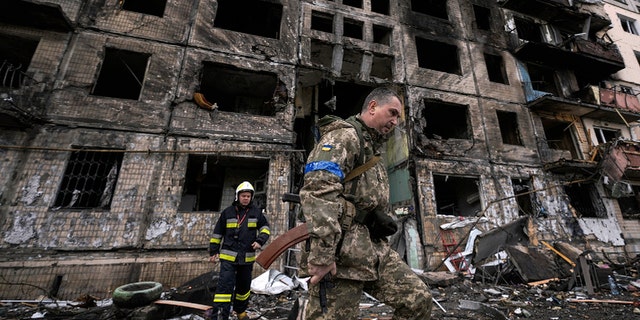 Ukrainische Soldaten und Feuerwehrleute inspizieren ein zerstörtes Gebäude nach einem Bombenanschlag in Kiew, Ukraine, Montag, 14. März 2022. 