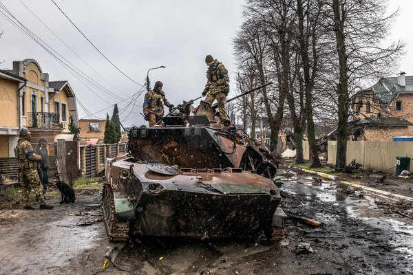 Ukrainian soldiers trying to salvage parts from a destroyed Russian armored vehicle in Bucha on Sunday.