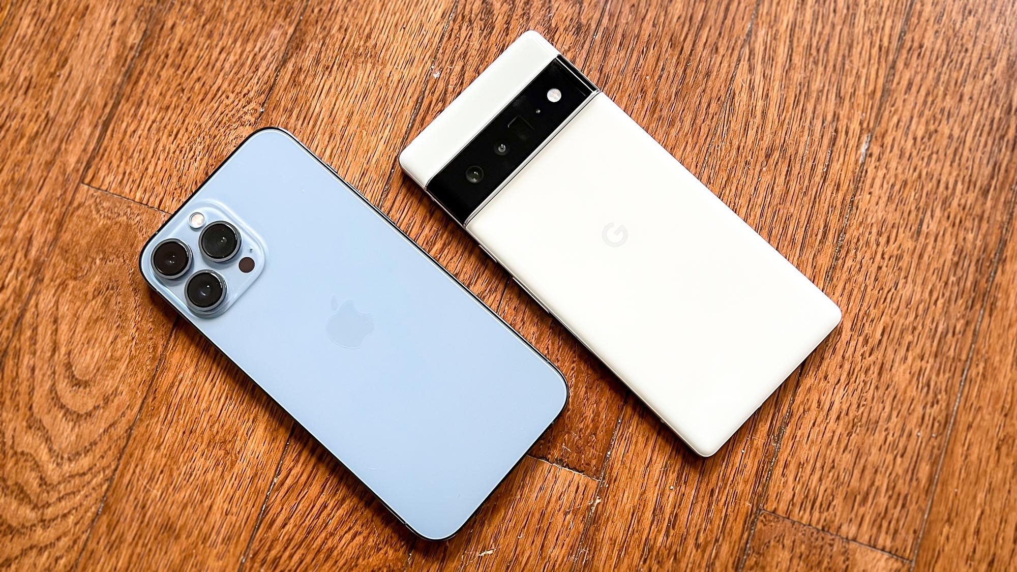 Pixel 6 Pro vs. iPhone 13 Pro Max: Beide Telefone liegen mit der Vorderseite nach unten auf einem Hartholzboden