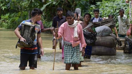 Menschen gehen am 18. Mai im Hochwasser im Distrikt Nagoon im indischen Bundesstaat Assam spazieren.
