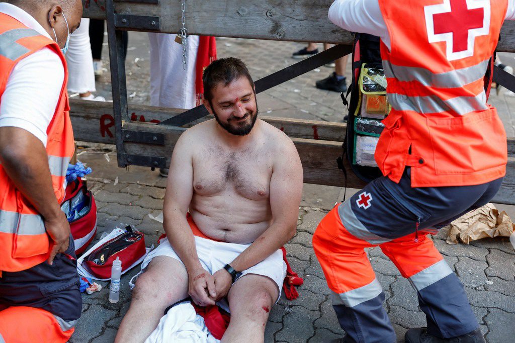 Ein Läufer ohne Hemd lächelt, obwohl er wegen seiner Verletzungen behandelt werden muss.